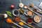 Top view of flat lay of assortment of legumes on black wooden tabletop background, in scoop and ladles and grater.