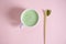 Top view. Flat lay. A bamboo scoop with powdered matcha and white cup of whipped japanese green tea over pink background