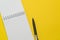 Top view, flat lay of blank open notepad and pen on bright vibrant yellow paper on office desk with copy space