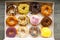 Top view flat lay of a colorful group of twelve delicious donuts in a white paper box on a wooden table. Collection of dozen