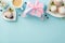 Top view flat lay of cupcakes, gifts, postcard, coffee, and gypsophila flowers on a pastel blue background