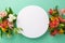 Top view flat lay of lively alstroemeria flowers on pastel teal background with empty circle for text or promotion