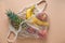 Top view flat lay string bag full of tropical fruits on a beige background