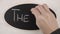 Top view flat lay of a woman`s hand writing The End words with white chalk on a blackboard