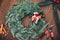 Top view florist making Christmas wreath on wooden table, flat lay tree branches secateurs, deer with red scarf