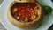 Top view focus in at exquisite decorated fish soup in brown bread bowl on white plate