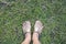 Top view of foot of woman wear brown slippers standing on the green greass