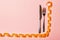 Top view of fork and knife and curled measuring tape on pink background. Diet concept with copy space