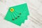 Top view of four green envelopes from recycled paper decorated with ladybirds and yellow flower craft ornaments on a white rustic