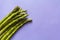 Top view of fresh green asparagus against purple background with copy space