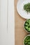 Top view of fresh microgreen on plate near bowls of green vegetables on beige napkin