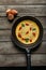 top view of fresh omelet with vegetables in frying pan on wooden table