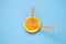 Top view of fresh orange fruit slice with two drinking straws isolated on blue