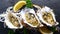 Top View of Fresh Raw Oysters in Shells with Lemon on Black Textured Slate Stone