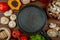 top view of fresh white mushrooms with tomatoes wooden mortar with dried herbs black peppercorns arranged around a frying pan on