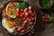 Top view the full English breakfast with bacon, eggs, toast, grilled tomatoes and beans, on a rustic background