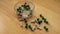 Top view of full thumb tacks in a transparent box and scattered on wooden background