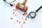 Top view of gavel, stethoscope and pill on white