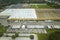 Top view of giant logistics center with many commercial trailer trucks unloading and uploading retail products for