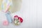 top view of gift box and red color roses with rolls of adhesive tape on white wooden background with copy space