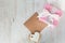 Top view of a gift box wrapped in pink dotted paper, heart shaped love cookie and an empty kraft card over a white wood background