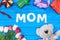 top view of gift boxes, teddy bear, tulips and word mom on blue table, mothers day concept