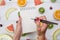 Top view of girl`s hands, placed on white desktop with fruits.