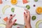 Top view of girl`s hands, placed on white desktop with fruits.