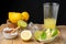 Top view of glass with lemonade, lemon wedges, lime, brown sugar, juicer and wooden bowl with lemons, black background,