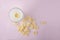 Top view of glass of milk and heap of corn flakes on the pink background