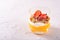 Top view of a glass of vegetarian dessert made of mango smoothie, ricotta, muesli and strawberry