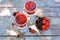 Top view of glasses full of raspberry and blackcurrant jam, vase full of fresh berries on wooden, grey texture