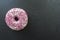 Top view of Glazed donut or Doughnut with pink sprinkles on black board