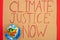 Top view of globe and placard with climate justice now lettering on red background, global warming concept