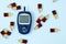 Top view of glucose meter and sweet jelly candies on blue background. Diabetes, high blood sugar level problem