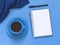 Top view goals list with notebook, cup of coffee on blue background. Flat lay, copy space