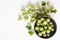 Top view of gooseberries with leaves, bowl full of seasonal fruits on the white surface