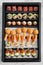 Top view of gourmet hors d\'oeuvres in a rectangular box. Mixed appetizers for takeout. Rows of tasty assorted canapés.