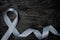 Top view of gray ribbon on dark wood background with copy space. Brain cancer tumor awareness concept.