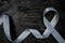 Top view of gray ribbon on dark wood background with copy space. Brain cancer tumor awareness concept.