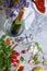 Top view of a gray table with plate, champagne, tomatoes, asparagus, glasses, corkscrew, beans on a gray background.