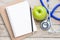 Top view green apple with blue stethoscope on wood table background