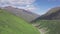 Top view of green mountain slopes on background of valley with rocky peaks. Clip. Lush grass growing on mountain slopes