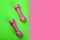 Top view of green sport mat and pink dumbbells neon pink background or set for pilates or fitness practice