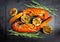 Top view: grilled lobsters with grilled garlic, grilled lime and rosemary branches on a slate plate on a black background