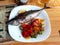 Top view of grilled Mullet fish with vegetables on a white plate