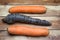 Top view on group of 3 isolated orange and black whole ripe fresh carrots, wooden background focus on center of black carrot