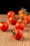 Top view of a group of cherry tomatoes with selective focus, on wooden table, black background, in vertical,