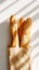 Top view of group of crispy baguettes in paper bag against white background with aesthetic shadows. Generative AI