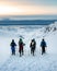 Top view of a group of hikers on snowy peaks of the mountains above the clouds